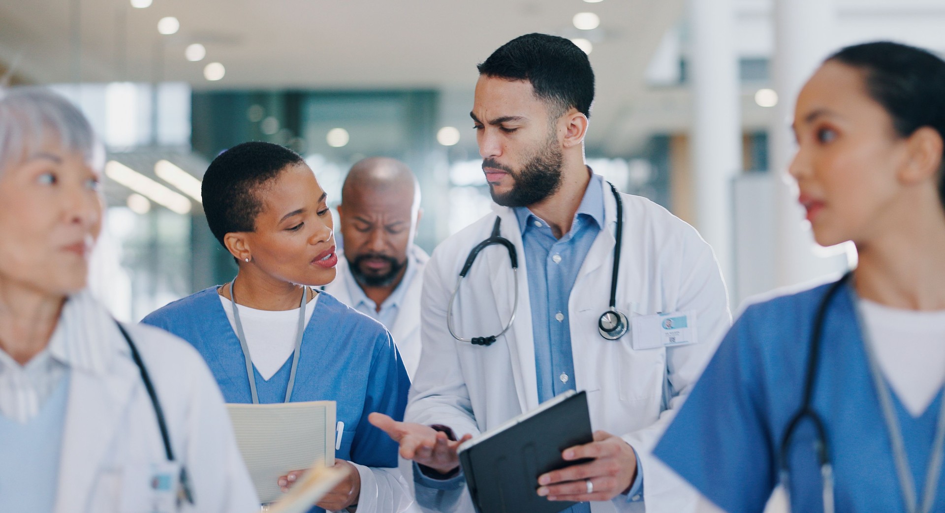 Meeting, tablet and doctors in discussion in hospital for medical results, consulting and research. Healthcare, clinic and men and women on digital tech for surgery schedule, telehealth and diagnosis